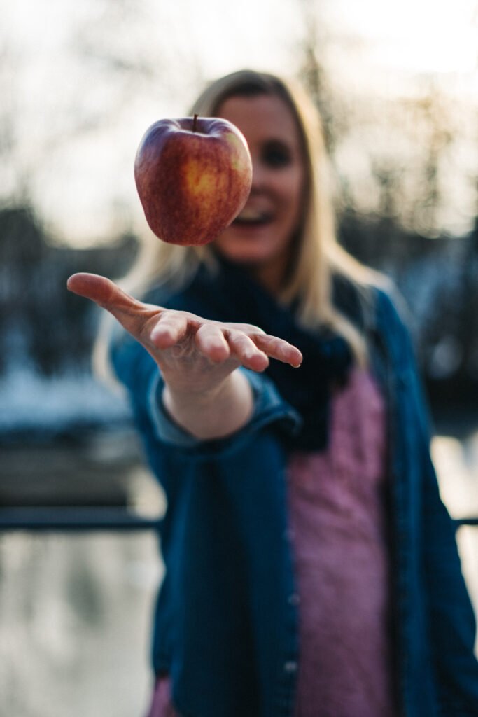 Frau wirft Apfel hoch