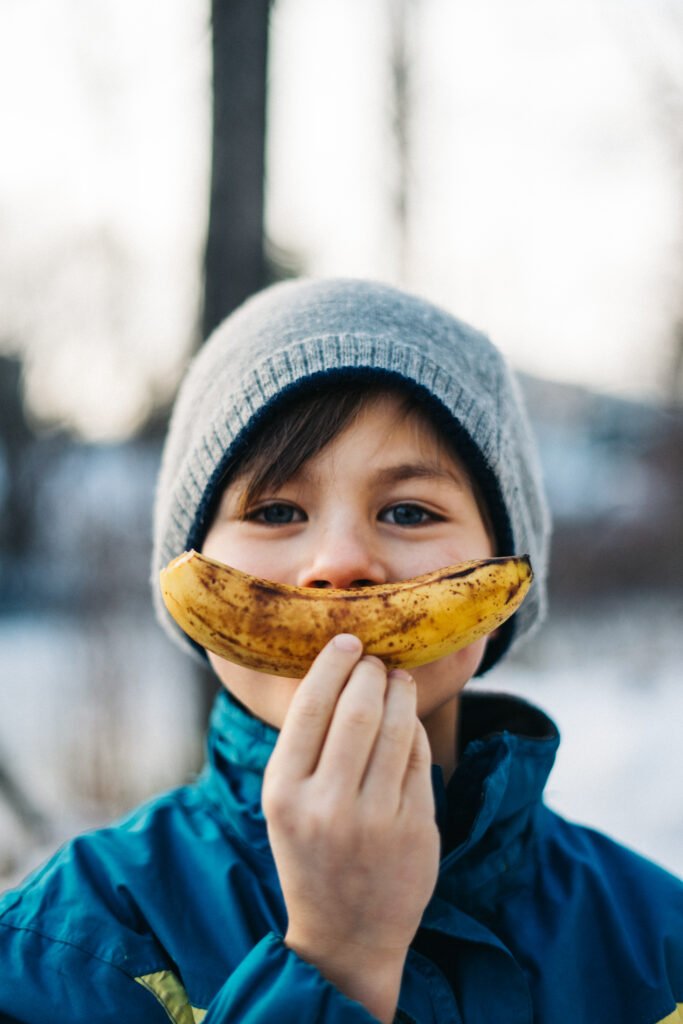 Junge hält Banane nach vorne